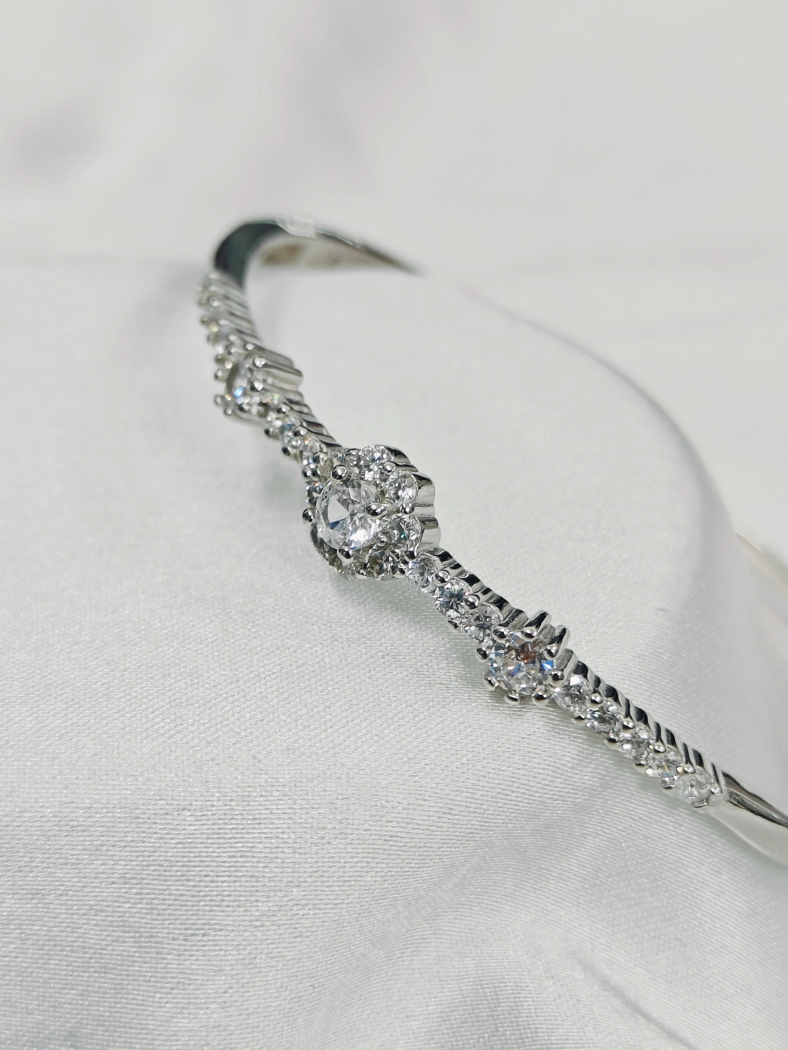 Silver bracelet with clear gemstones on a light gray background